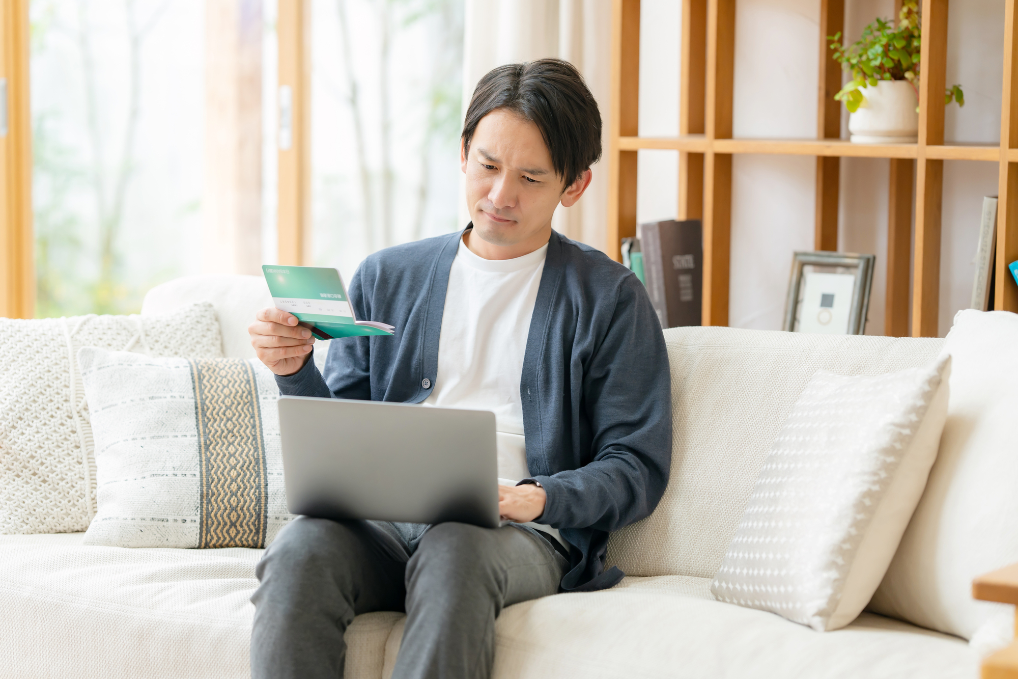 失業給付金の待機期間とは?通帳を片手に調べ物をする男性