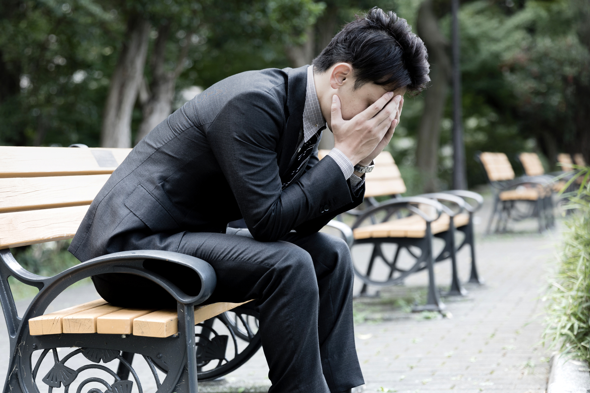ベンチに座って落ちこんでいる男性