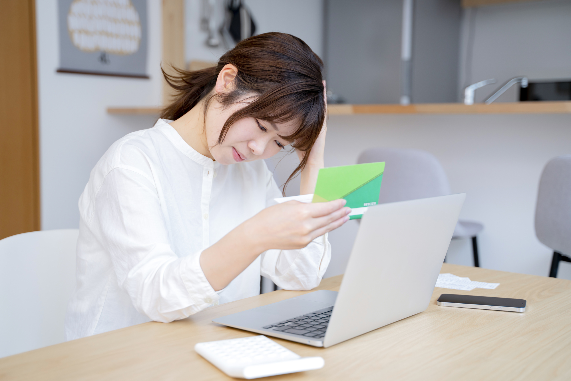 通帳を見て悩んでいる女性